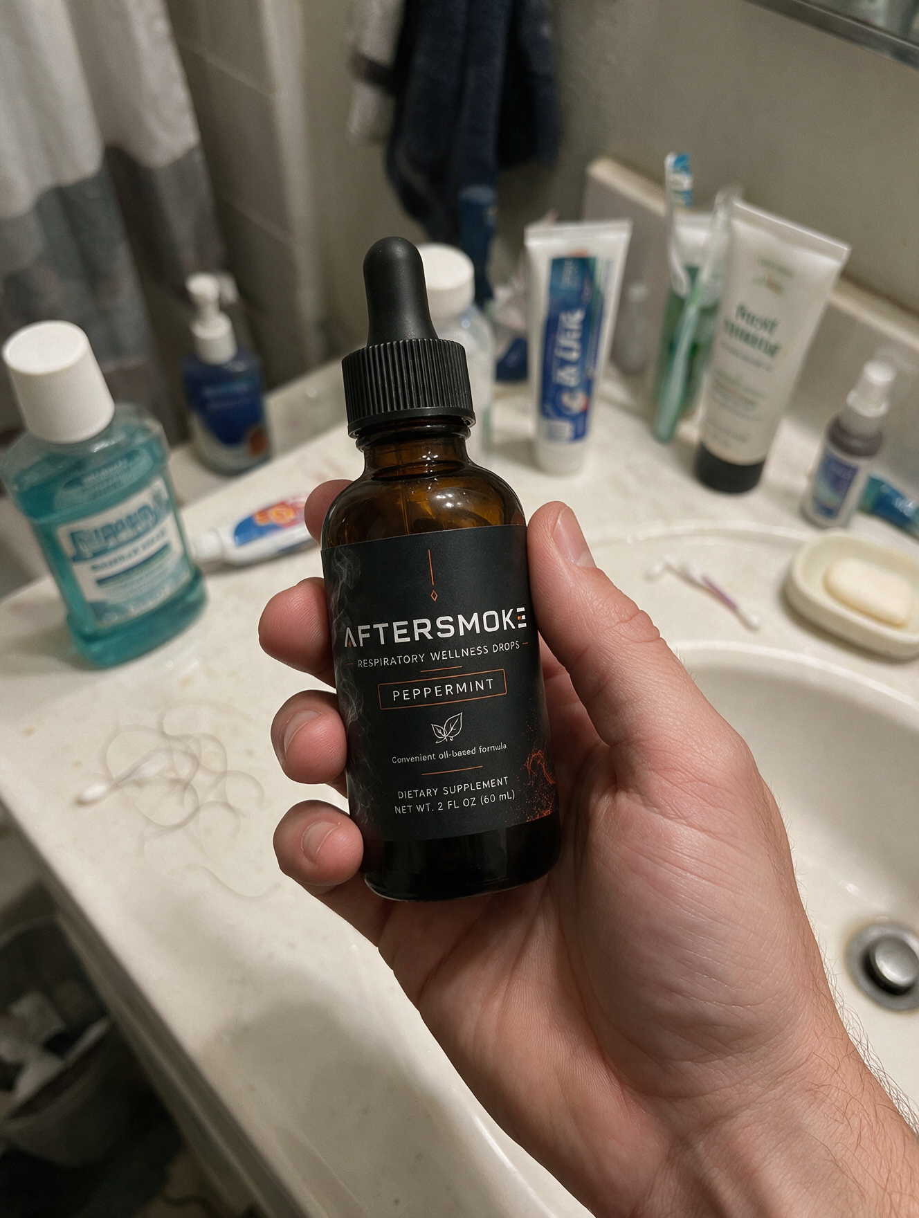 AfterSmoke bottle held in hand over a bathroom sink