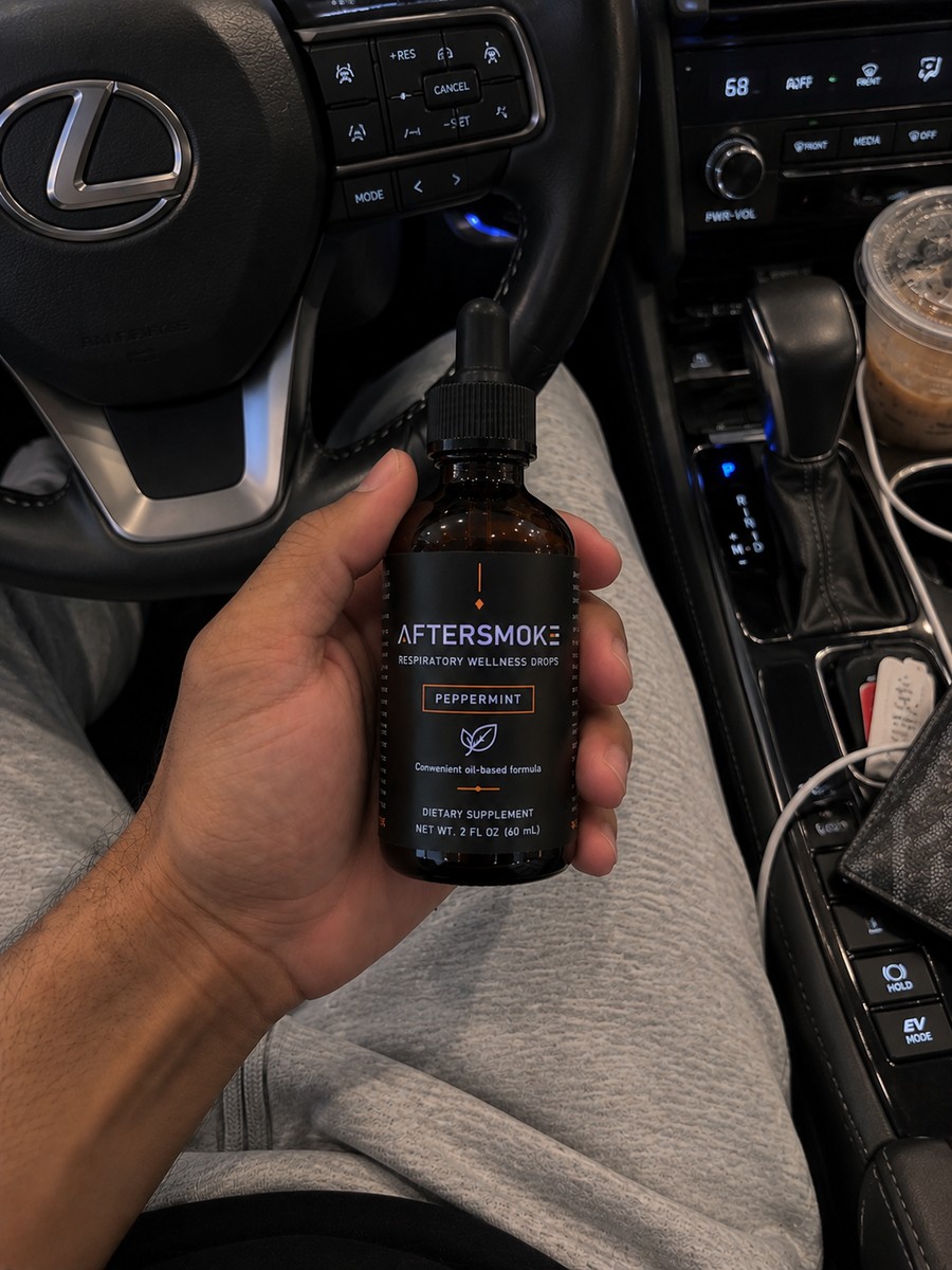 AfterSmoke bottle held in hand in a car