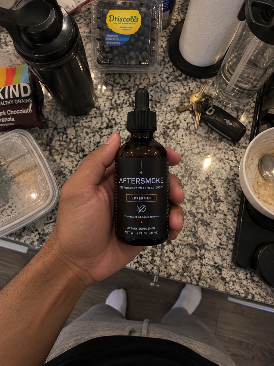 AfterSmoke bottle held in hand over a kitchen counter