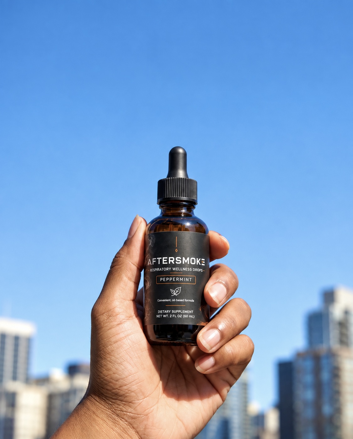 A hand holding a bottle of AFTERSMOKE Respiratory Wellness Drops against a blue sky and city skyline